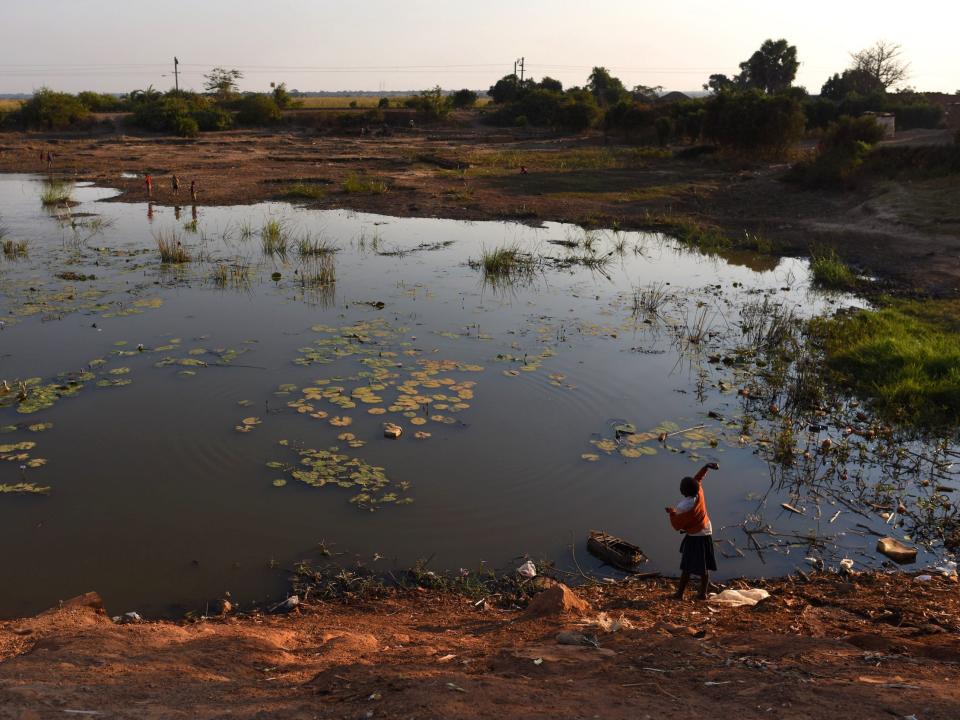 A child throws a stone into the Kapolowe River