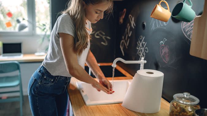 Woman washing hands in kitchen.