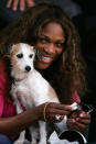 Serena Williams holds her dog Jackie, as her sister Venus Williams of the USA plays against Sania Mirza of India during the Bank of the West Classic tennis tournament on July 27, 2005 at Stanford University in Palo Alto, California. (Photo by Jed Jacobsohn/Getty Images)