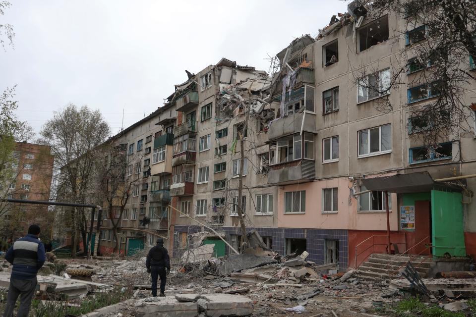 People look at a building damaged by a Russian rocket attack in Sloviansk, Donetsk region, Ukraine, Friday, Apr. 14, 2023. The death toll from Russian missile strikes on eastern Ukraine's city of Sloviansk rose to 11 Saturday as rescue crews tried to reach people trapped in the rubble of an apartment building, Ukrainian authorities said.