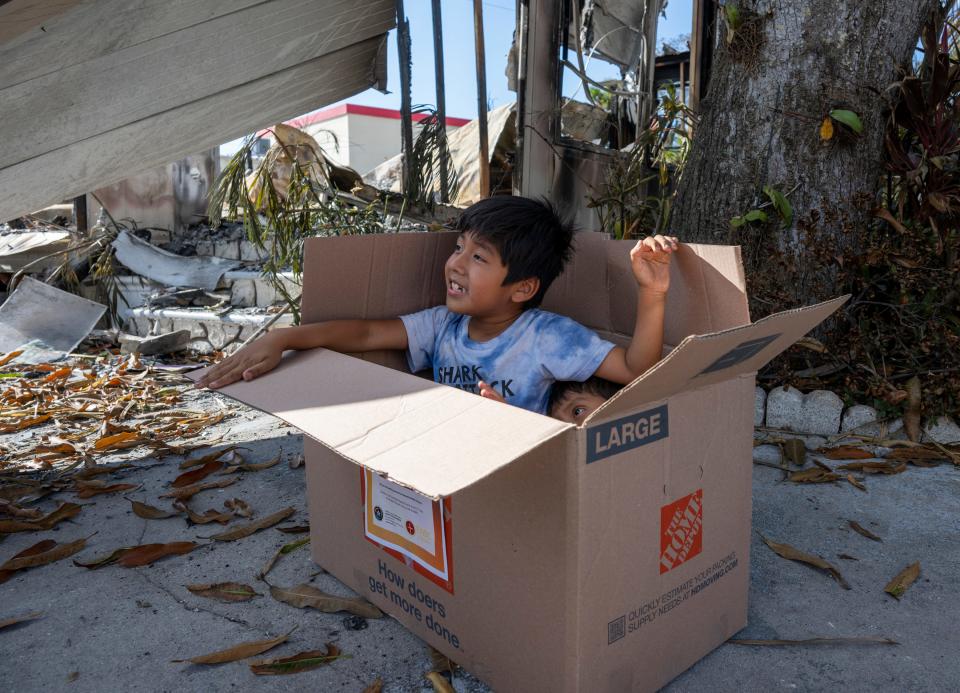 Ethan Buatista, 6, left, and his brother Enzo Buatista, 3, play in a box used to deliver food to residents of the flood-damaged Harmony Shores mobile home park in East Naples, Fla., on Wednesday, Oct. 5, 2022.