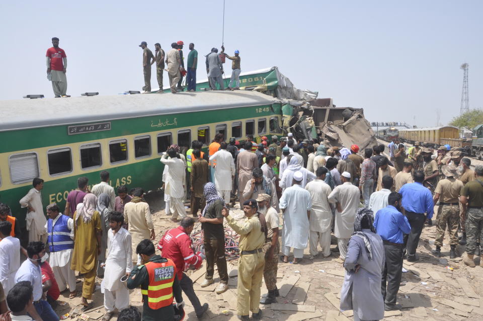 Pakistani officials and volunteers work at a train crash site in Rahim Yar Khan, Pakistan, Thursday, July 11, 2019. A passenger train rammed into a freight train in southern Pakistan on Thursday, killing many people and injuring others, an official said. (AP Photo/Waleed Saddique)