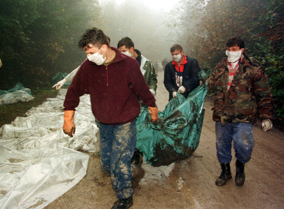 FILE - In this Oct. 9, 1996. file photo, Bosnian workmen carry the body of a Muslim allegedly killed by Bosnian Serbs in 1992, dug out from a cave together with seventy others, in Laniste, 170 kilometers (105 miles) northwest of Sarajevo, Bosnia. While it brought an end to the fighting, the Dayton peace agreement baked in the ethnic divisions, establishing a complicated and fragmented state structure with two semi-autonomous entities, Serb-run Republika Srpska and a Federation shared by Bosniak and Croats, linked by weak joint institutions. (AP Photo/Darko Bandic, File)