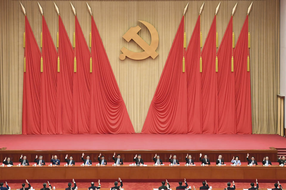 In this photo released on 11 Nov. 2021 by Xinhua News Agency, members of the Standing Committee of the Political Bureau of the Communist Party of China (CPC) Central Committee, including Chinese President Xi Jinping, center on stage, raise their hands to vote as they attend the sixth plenary session of the 19th Central Committee of the Communist Party of China (CPC) in Beijing. Words on the banner reads "The 19th Communist Party of China Central Committee sixth plenary session" (Zhai Jianlan/Xinhua via AP)