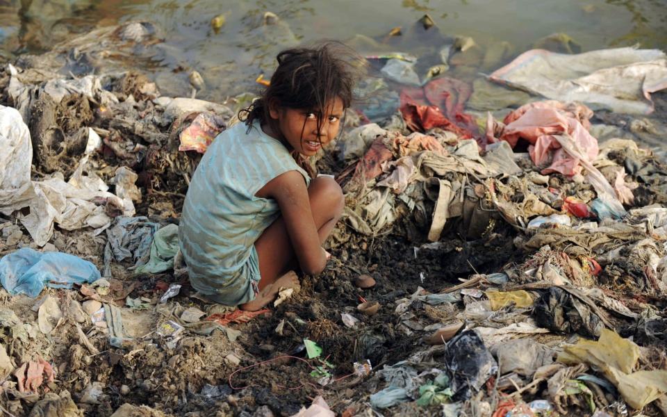 An Indian child searches for coins used in ritual offerings by Hindu devotees on the polluted banks of the river Yamuna in Allahabad - DIPTENDU DUTTA /AFP