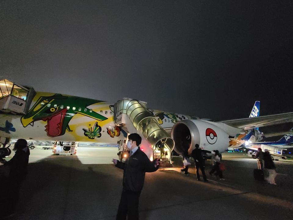 Exterior of pokemon aircraft with people coming off of it at night 