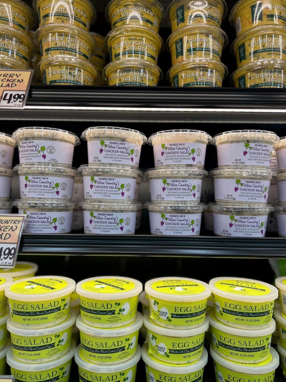 Shelves stocked with various sizes of egg salad containers at a grocery store