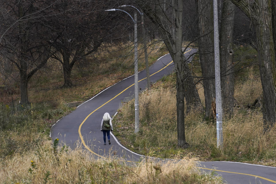 Phyllis Marder walks along a River Park bike trail Wednesday, Nov. 11, 2020, in Chicago. She’ll be working as a coronavirus contract tracer for a nearby county. (AP Photo/Charles Rex Arbogast)