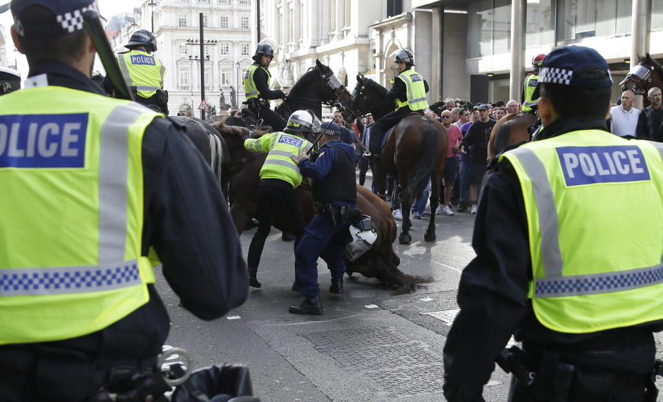 A police officer is dismounted as he helps stop a breakaway from the main Football Lads Alliance march, as they attempt to get close to a rival anti-fascist demonstration in London, Saturday, Oct. 13, 2018. (AP Photo/Alastair Grant)