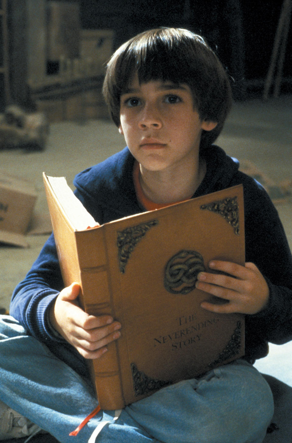 Barret as a child holding the book "The Neverending Story"