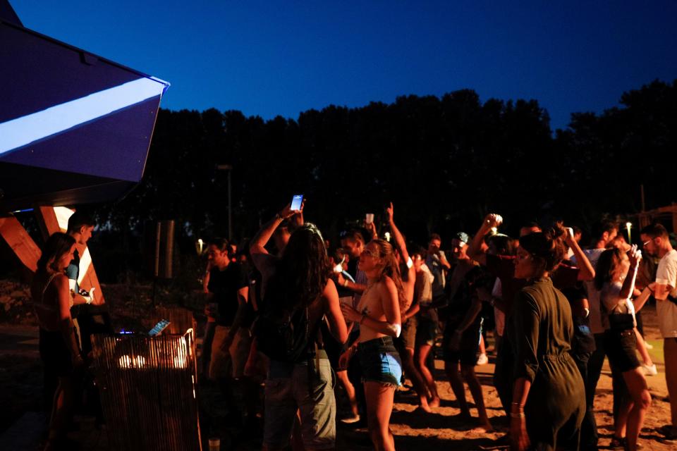 People dance and enjoy an open air party in Saint-Denis, north of Paris on August 1st, 2020. - It took an epidemic, the closure of clubs and a relative permissiveness of the authorities for Paris to become in one summer a sanctuary of the "free party", these underground techno parties, some of which gathered in July, up to a thousand of people. The epicenter of this phenomenon is in the Bois de Vincennes, where a dozens of musical scenes are set illegally in the depths of the woods. (Photo by GEOFFROY VAN DER HASSELT / AFP) (Photo by GEOFFROY VAN DER HASSELT/AFP via Getty Images)