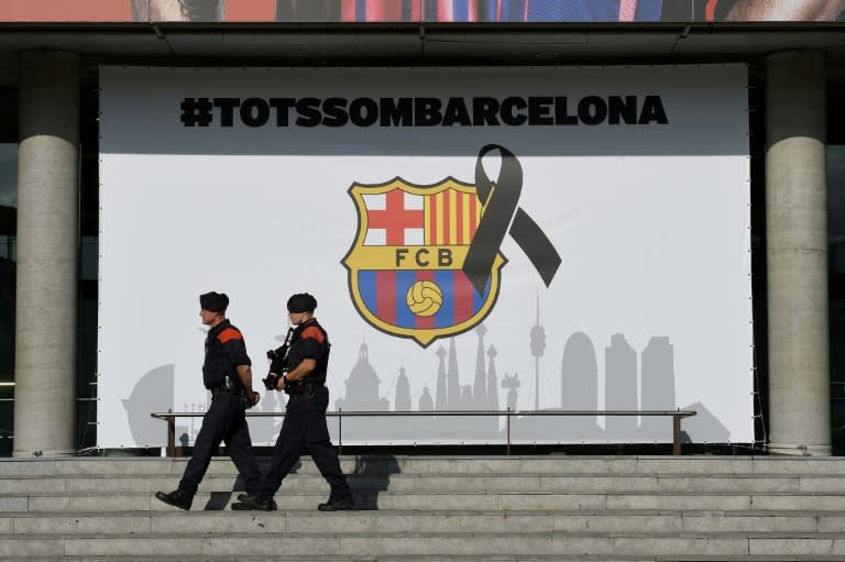 Armed Catalan policemen pass by the FC Barcelona logo with a black ribbon and a message reading, "We are all Barcelona" at the Camp Nou stadium in Barcelona on August 20, 2017