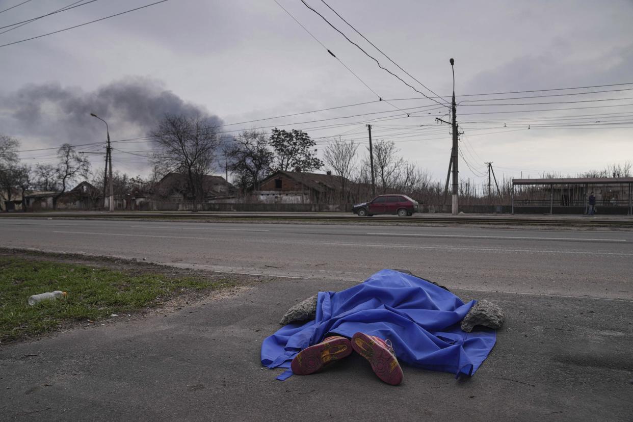 The dead body of a person lies covered in the street in Mariupol, Ukraine, Monday, March 7, 2022.