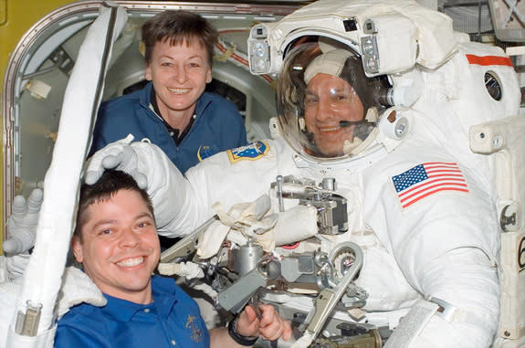 Office, are seen together on board the International Space Station assisting STS-123 mission specialist Rick Linnehan after a spacewalk in March 2008.