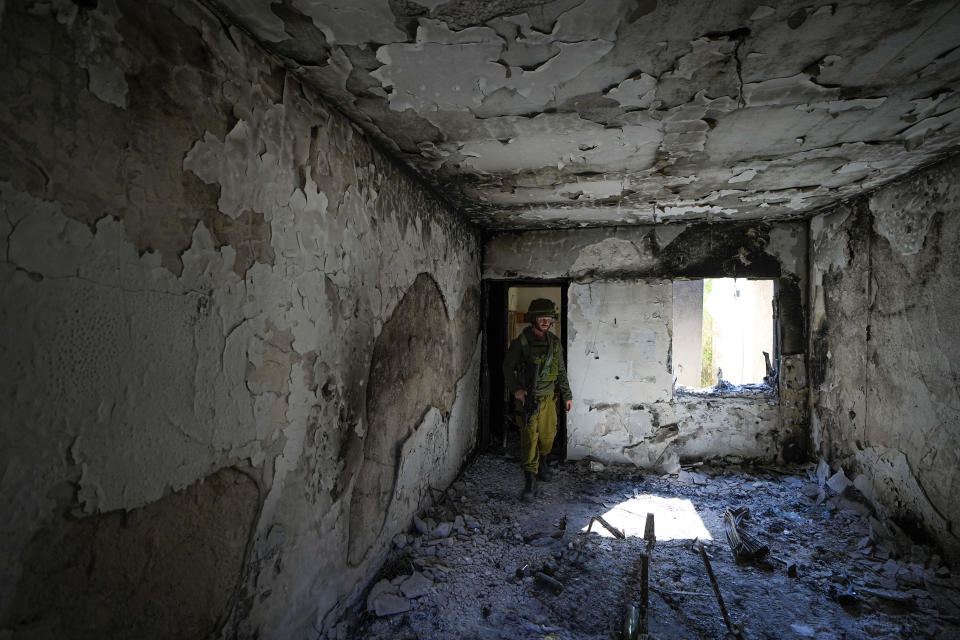 An Israeli soldier inspects a house damaged by Hamas militants in Kibbutz Kfar Azza, Israel, Wednesday, Oct. 18, 2023. The Kibbutz was overrun by Hamas militants from the nearby Gaza Strip on Oct .7, when they killed and captured many Israelis. (AP Photo/Ariel Schalit)