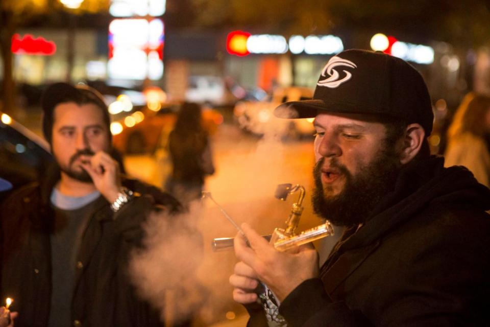 People smoke cannabis on the street in Toronto after the drug was legalised at midnight (Chris Young/AP)