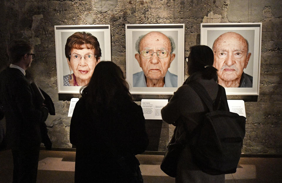 Visitors look at portrait photos of the exhibition 'Survivors - Faces of Life after the Holocaust' at the former coal mine Zollverein in Essen, Germany, Tuesday, Jan. 21, 2020. The world heritage landmark Zollverein shows 75 years after the liberation of the Nazi death camp Auschwitz-Birkenau, 75 portraits of Jewish survivors, photographed in Israel by German artist Martin Schoeller. (AP Photo/Martin Meissner)