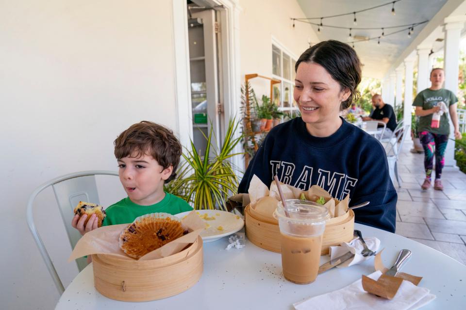 Hudson Hornick, 3, eats his favorite, a blueberry muffin next to his mother, Karlee Lebinson during a visit the Perk Coffee House on April 18, 2024 in Tequesta, Florida.