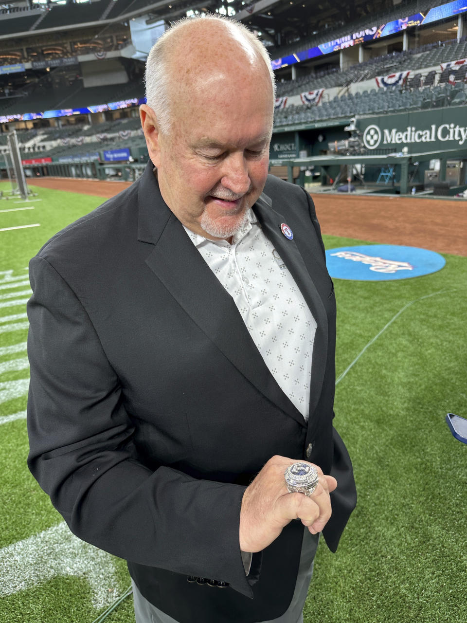 Texas Rangers longtime public address announcer Chuck Morgan admires his World Series championship ring, Saturday, March 30, 2024 in Arlington Texas. The Texas Rangers and staff will receive their World Series championship rings during a pre-game ceremony before the Texas Rangers take on the Chicago Cubs in a baseball game. (AP Photo/Stephen Hawkins)