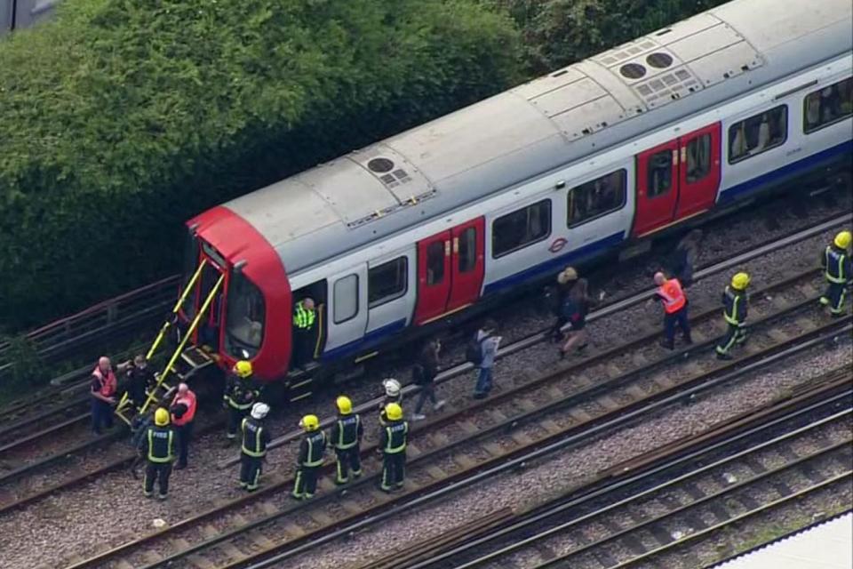 Emergency workers help people to disembark a train near the Parsons Green Tube bombing (Pool via AP)