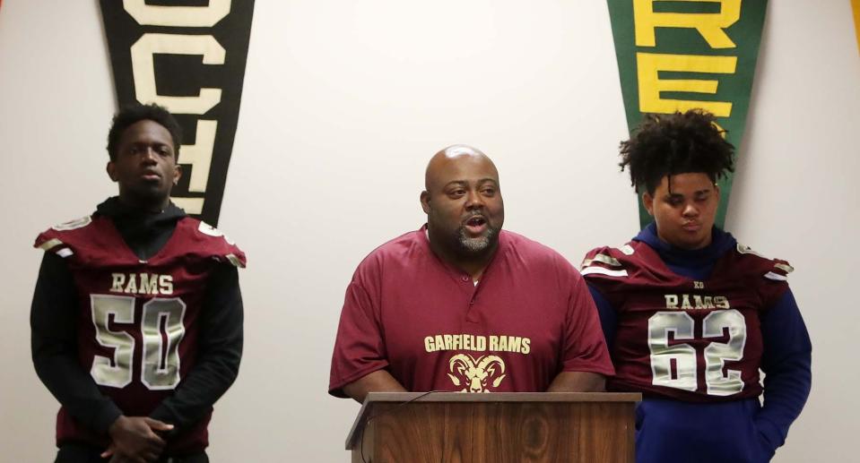 Garfield assistant football coach Ellery Bradford, center speaks during the Akron Public Schools Football Media Day as he stands between players Klinsman Kodjoe, left, and Drew Terry on Wednesday in Akron. 
