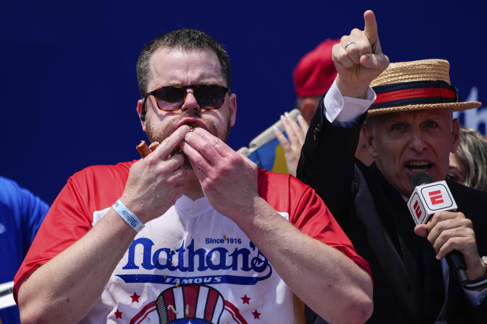 Patrick Bertoletti llena su boca de hot dogs durante el concurso anual de comer los perritos calientes de Nathan's por el Día de la Independencia de Estados Unidos, el jueves 4 de julio de 2024, en Coney Island, Nueva York. (AP Foto/Julia Nikhinson)