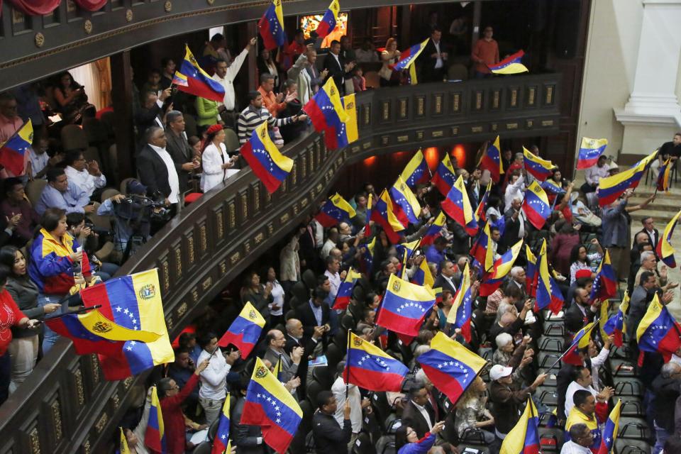 Members of the National Constituent Assembly wave Venezuelan flags during a session by the legislative body that is stacked with government allies that rivals the opposition-controlled National Assembly in Caracas, Venezuela, Monday, Aug. 12, 2019. Legislators loyal to Venezuelan President Nicolás Maduro on Monday stripped immunity from four opposition lawmakers accused of treason amid a struggle for control of the crisis-stricken nation, bringing to 18 the number of opposition politicians Maduro's government has threatened with criminal prosecution this year. (AP Photo/Leonardo Fernandez)