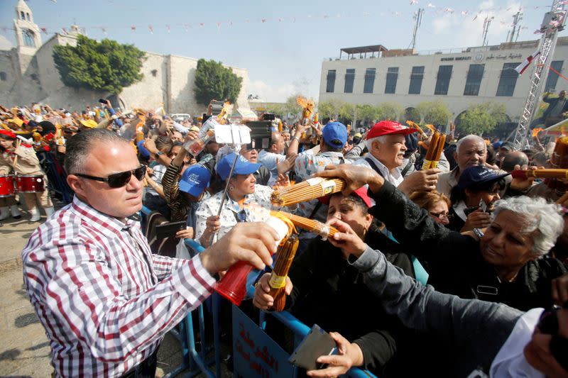 People light candles as they celebrate the arrival of the Holy Fire outside the Church of the Nativity in Bethlehem