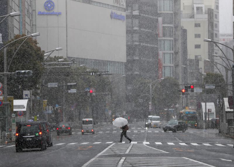 A man walks past on a nearly empty street in a snow fall during a coronavirus disease (COVID-19) outbreak in Tokyo