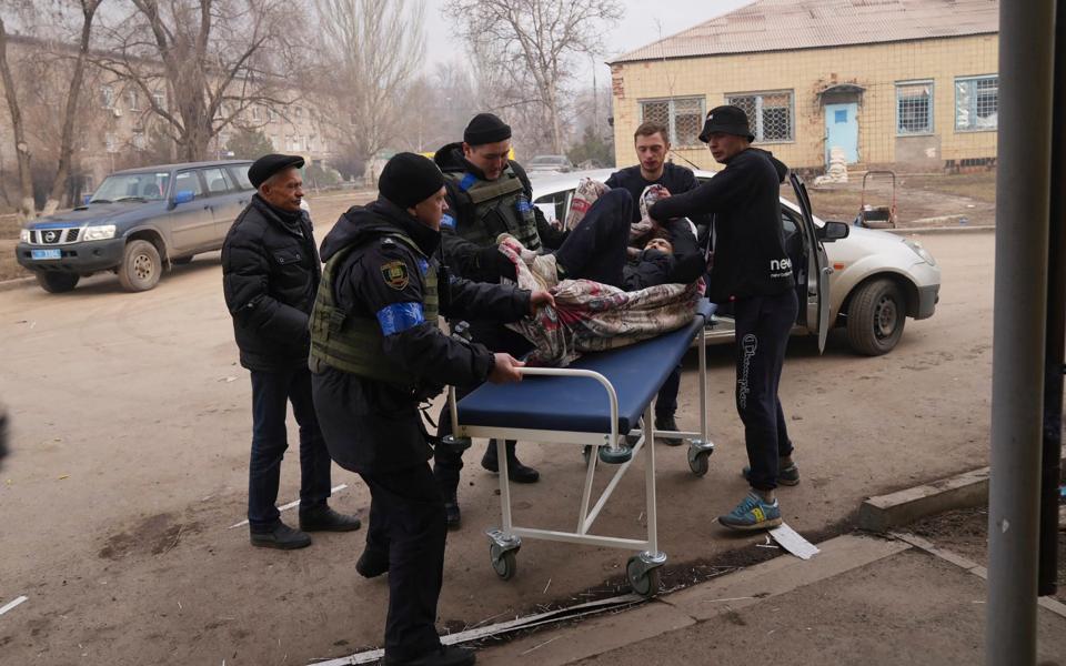 Ukrainian servicemen and volunteers carry a man injured during a shelling attack into hospital number 3 in Mariupol, Ukraine - Evgeniy Maloletka/AP