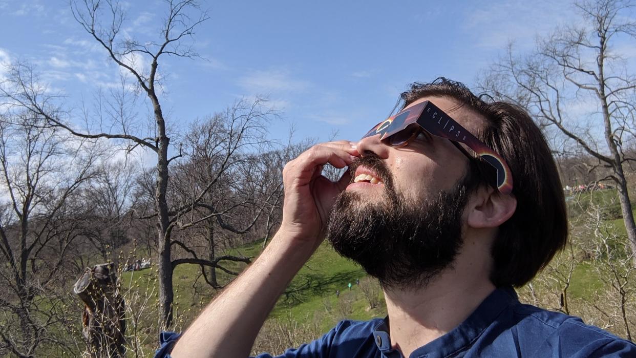  A handsome young man looks up at the sun through solar eclipse glasses on April 8, 2024. 