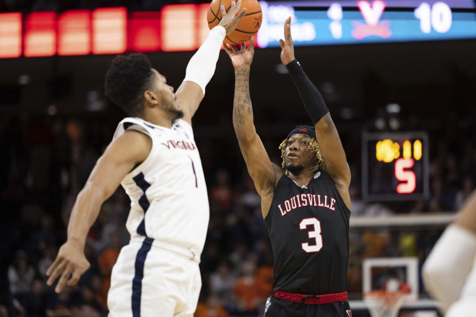 Virginia's Jayden Gardner (1) blocks a shot by Louisville's El Ellis (3) during the first half of an NCAA college basketball game in Charlottesville, Va., Saturday, March 4, 2023. (AP Photo/Mike Kropf)