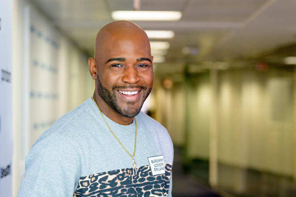 A smiling Karamo wearing a "Burberry London England" shirt and a necklace