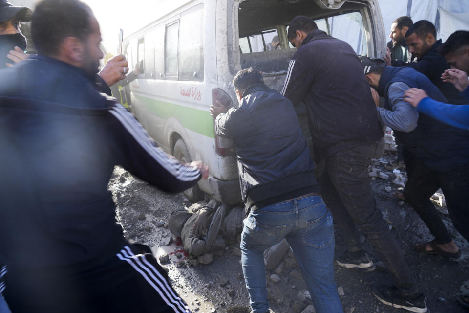 Palestinians push an ambulance to release a man at Al-Aqsa Hospital In Deir al Balah, Gaza Strip, moments after an Israeli strike hit a building next to it on Wednesday, Jan. 10, 2024. (AP Photo/Hatem Moussa)