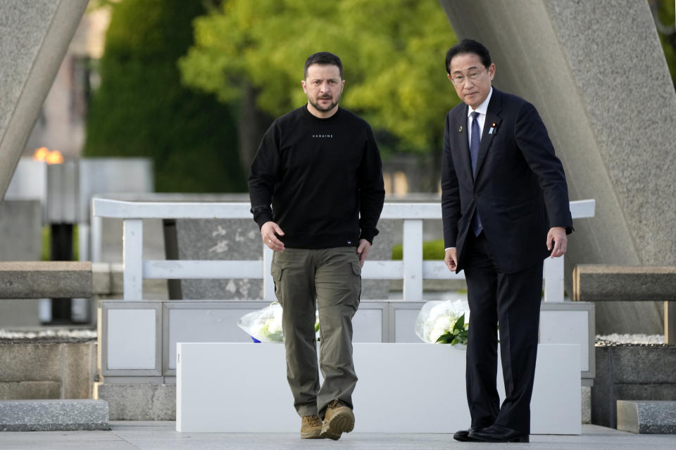 Ukrainian President Volodymyr Zelenskyy, left, is escorted by Japanese Prime Minister Fumio Kishida to lay flowers in front of the Cenotaph for the Victims of the Atomic Bomb at the Hiroshima Peace Memorial Park after he was invited to the Group of Seven (G7) nations' summit in Hiroshima, western Japan Sunday, May 21, 2023. The Atomic Bomb Dome is seen in the background. (AP Photo/Eugene Hoshiko, Pool)