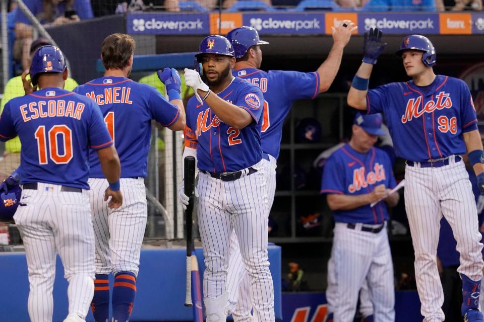 New York Mets' Eduardo Escobar (10), Jeff McNeil (1) and Pete Alonso, second from front right, are greeted by teammates Dominic Smith (2) and Hayden Senger (98) after scoring on a double hit by J.D. Davis in the third inning of a spring training baseball game against the Miami Marlins, Thursday, March 24, 2022, in Port St. Lucie, Fla.