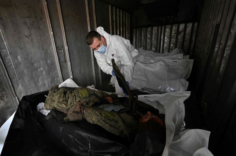 Expertos forenses ucranianos examinan el cuerpo de un soldado ruso exhumado en el pueblo de Zavalivka, al oeste de Kiev, en un vagón refrigerado apilado con los muertos rusos el 11 de mayo de 2022.