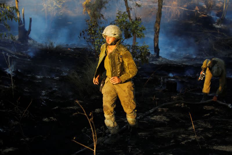 Israeli soldiers try to extinguish fire, on the Israeli side of the border between Israel and the Gaza Strip