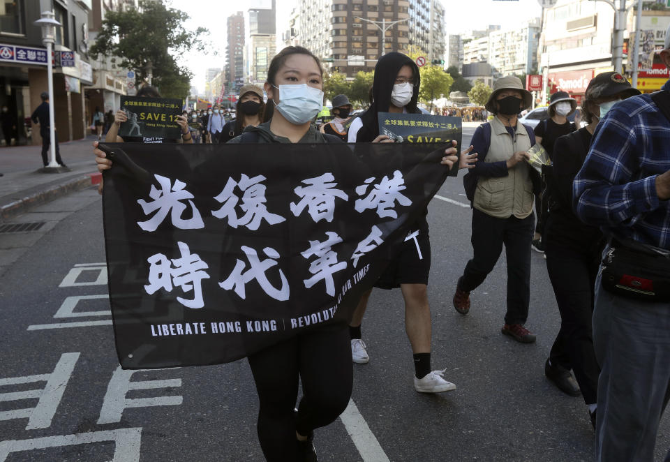 FILE - In this Oct. 25, 2020, file photo, protester holds a slogan reading "Liberate Hong Kong" during a march to demand mainland China to release 12 Hong Kong protesters in Taipei, Taiwan. Hong Kong’s government on Friday, May 21, 2021, said it has pulled all of its staff out of Taiwan and accused the island’s government of having “grossly interfered” in the semi-autonomous Chinese city’s internal affairs. (AP Photo/Chiang Ying-ying, File)