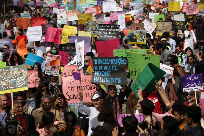 Women and men carry signs as they take part in an Aurat March, or Women's March in Lahore,