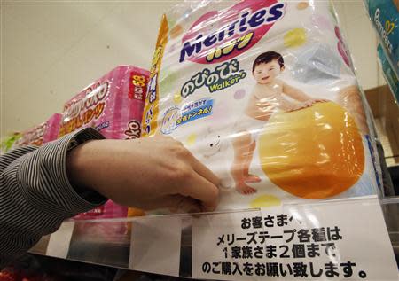 An Aeon Co Ltd's supermarket staff adjusts a slip of paper informing the two-package-per-family limit on Kao Corp's 'Merries' brand diapers on a display shelf at its Chiba outlet, east of Tokyo, March 31, 2014. REUTERS/Yuya Shino