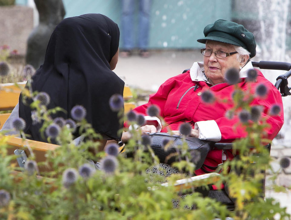 In this Aug. 30, 2018 photo a young migrant from Africa talks to an old woman she is taking care of in Flen, some 100 km west of Stockholm, Sweden. The town has welcomed so many asylum seekers in recent years that they now make up about a fourth of the population. (AP Photo/Michael Probst)