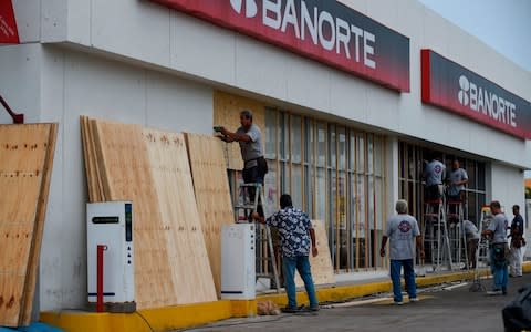 Workers protect a storefront at Mazatlan port in Sinaloa state, Mexico - Credit: Alfredo Estrella/AFP