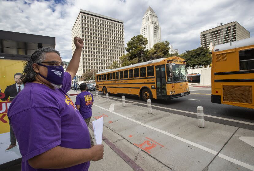 LOS ANGELES, CA - AUGUST 13: Max Arias, SEIU Local 99 Executive Director cheers on school buses as they caravan around the Federal Building in downtown Los Angeles where a press conference was held to demand that Congress and California legislators provide sufficient funding to ensure all students have all the support they need for distance learning and the eventual safe return to -in-person classes. (Mel Melcon / Los Angeles Times)