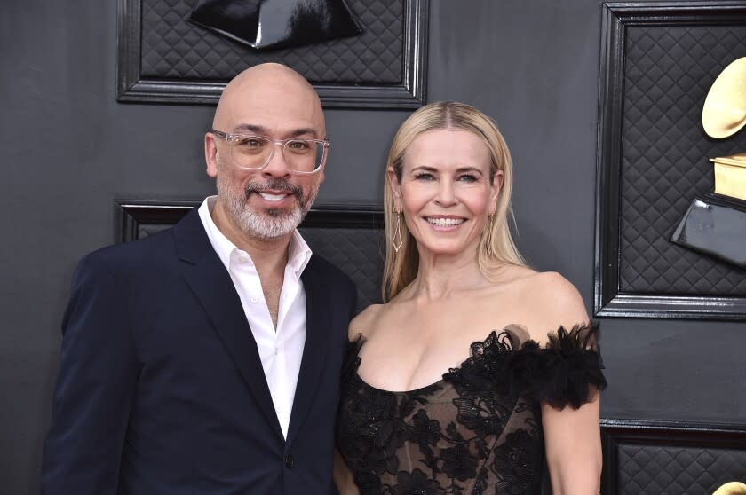 A man in a suit stands next to a woman in a lacy black dress