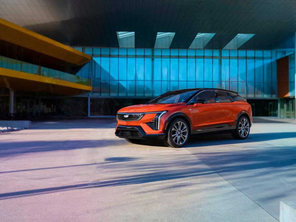 A front three-quarters view of the 2025 Cadillac Optiq compact SUV in Monarch Orange.