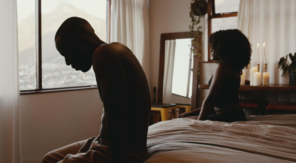 man and woman sitting apart from each other at the edge of the bed