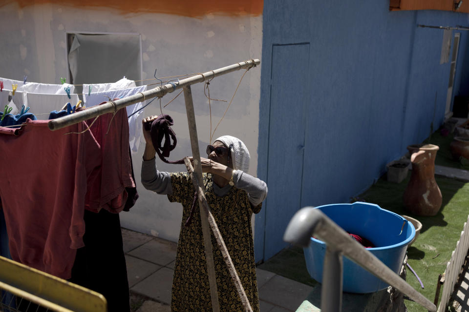 A woman from the the African Hebrew Israelites of Jerusalem community in hangs her laundry in the Village of Peace in Dimona, Israel, Tuesday, March 28, 2023. The community first made their way to Israel from the United States in the 1960s. While they do not consider themselves Jewish, they claim an ancestral connection to Israel. (AP Photo/ Maya Alleruzzo)