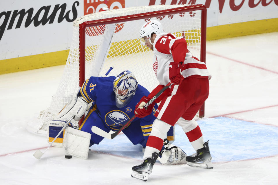 Buffalo Sabres goaltender Eric Comrie (31) makes a save on Detroit Red Wings left wing J.T. Compher (37) during the third period of an NHL hockey game Tuesday, Dec. 5, 2023, in Buffalo, N.Y. (AP Photo/Jeffrey T. Barnes)