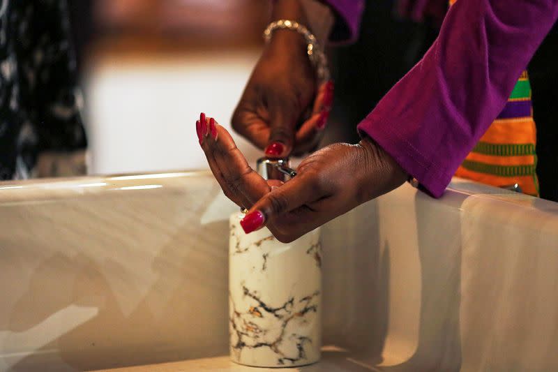 Eucharistic ministers use hand sanitizer before Communion as a sanitary precaution at Our Lady of Lourdes Catholic church in Atlanta